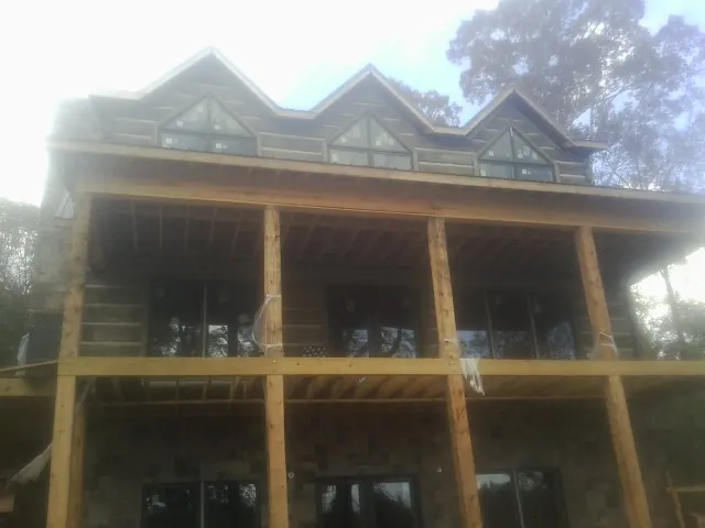 Dormers and porch framing on a large log home under construction — Roof Coating work by our crew in Saint Benedict